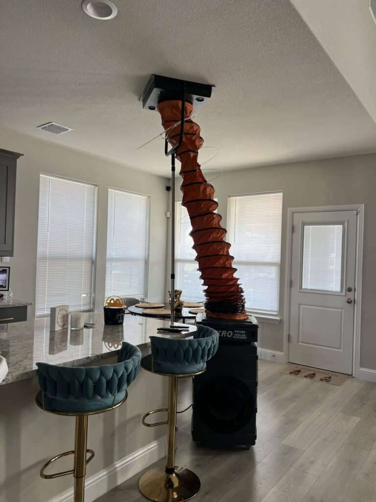 Air duct cleaning service setup with NIKRO vacuum and orange collection hose in an elegant residential living room