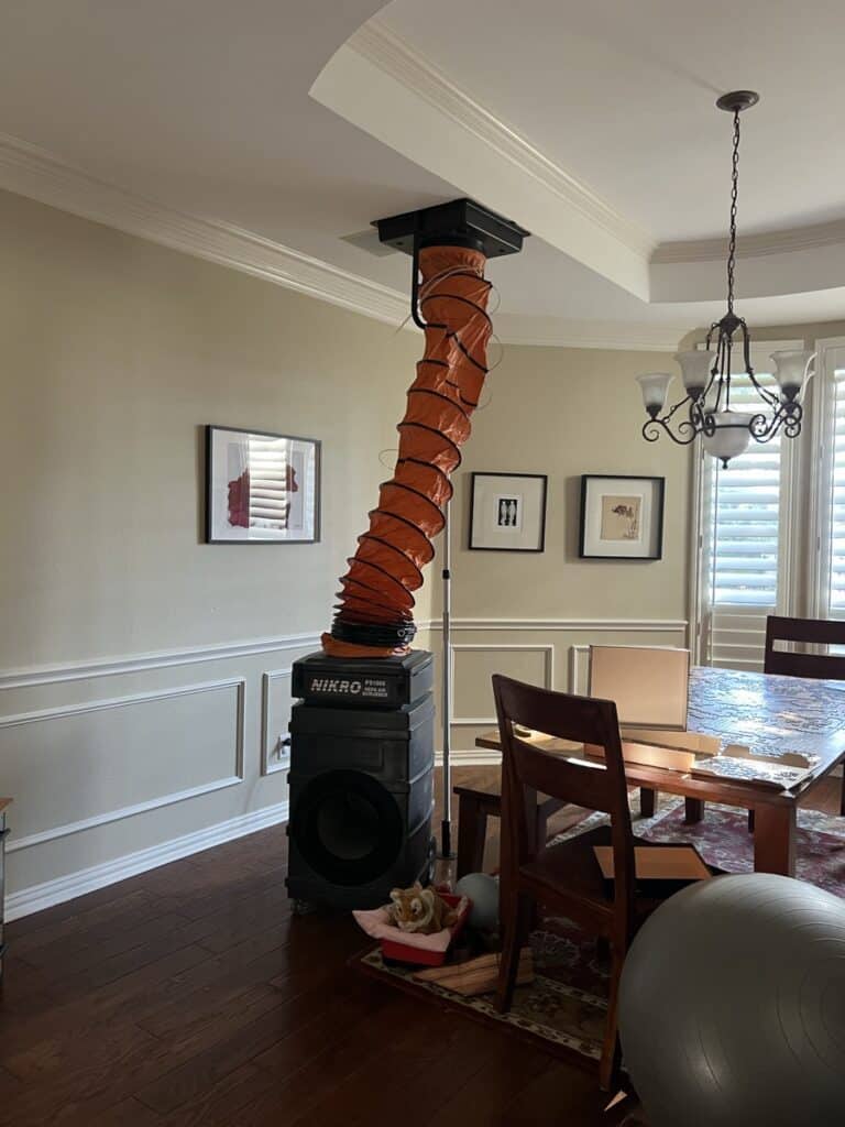 Professional air duct cleaning setup in a Dallas home with NIKRO vacuum system and orange collection hose