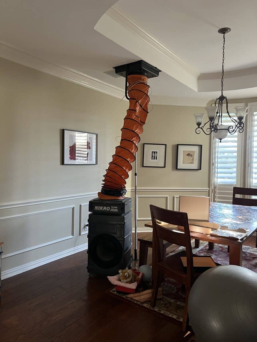 Professional air duct cleaning setup in a Dallas home with NIKRO vacuum system and orange collection hose