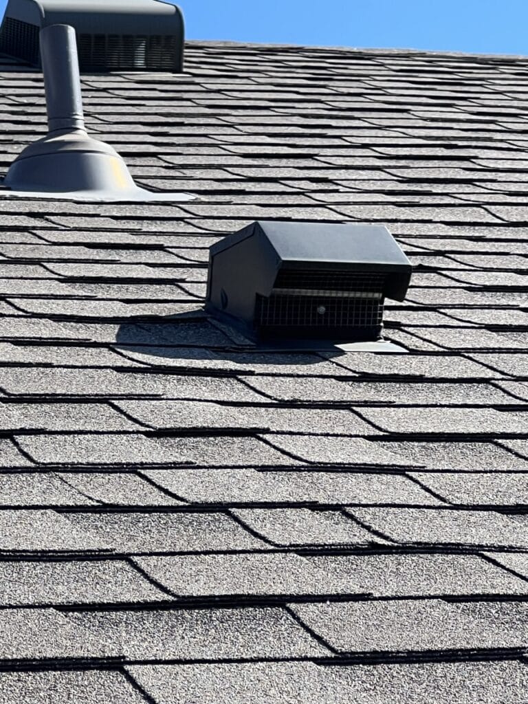Dryer vent exhaust cap installed on residential roof shingles showing exterior ventilation