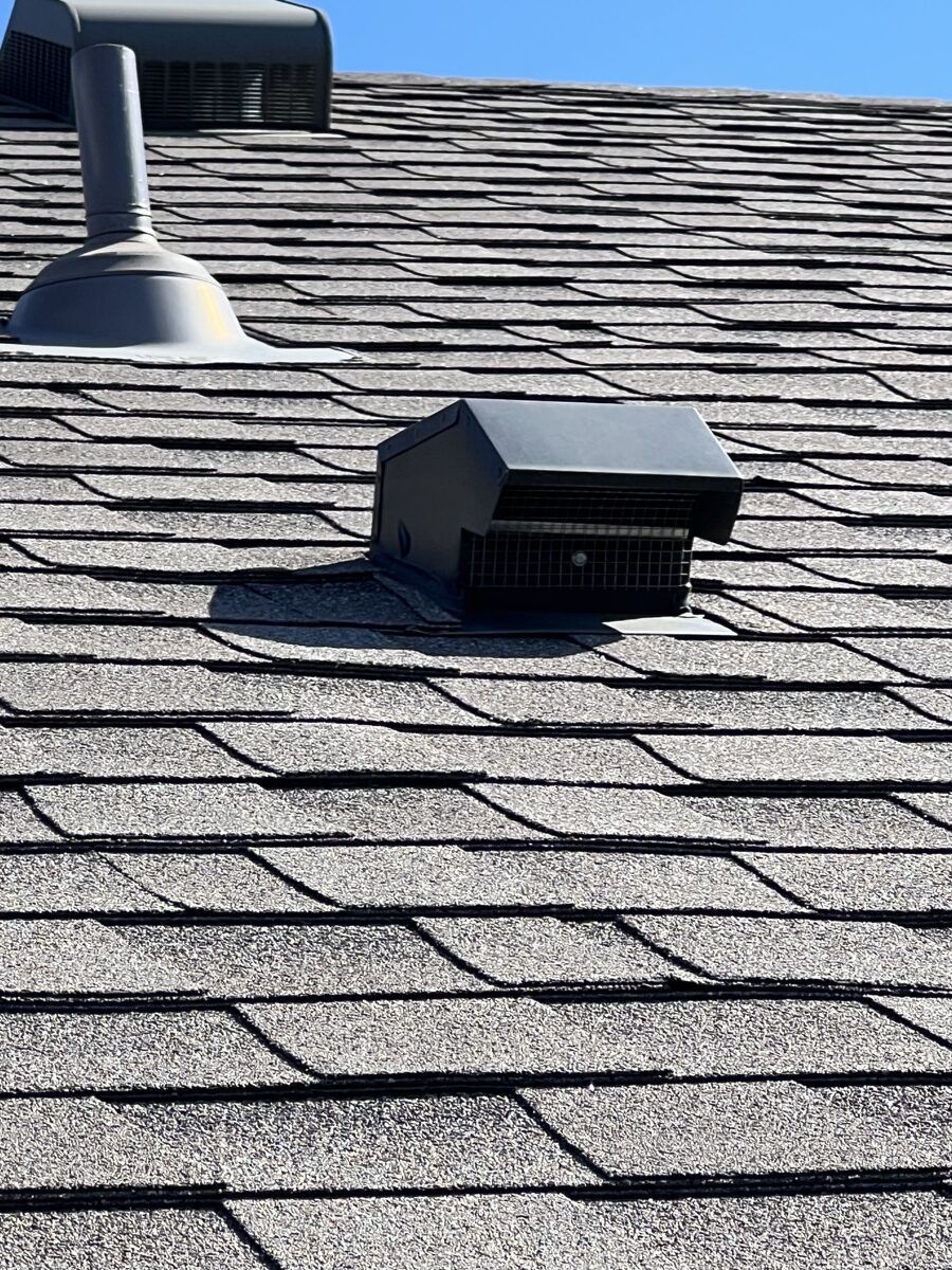 Dryer vent exhaust cap installed on residential roof shingles showing exterior ventilation