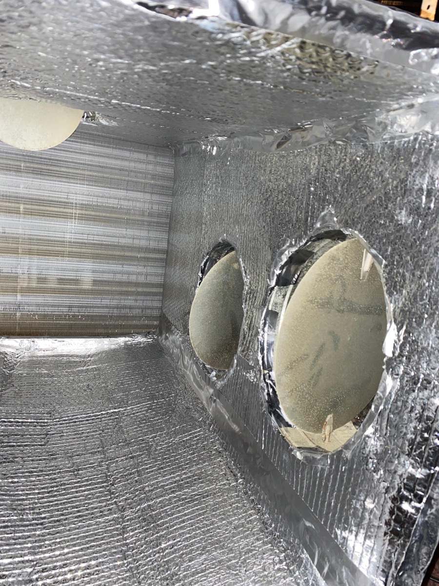 Interior view of clean plenum box showing circular duct openings and reflective insulation