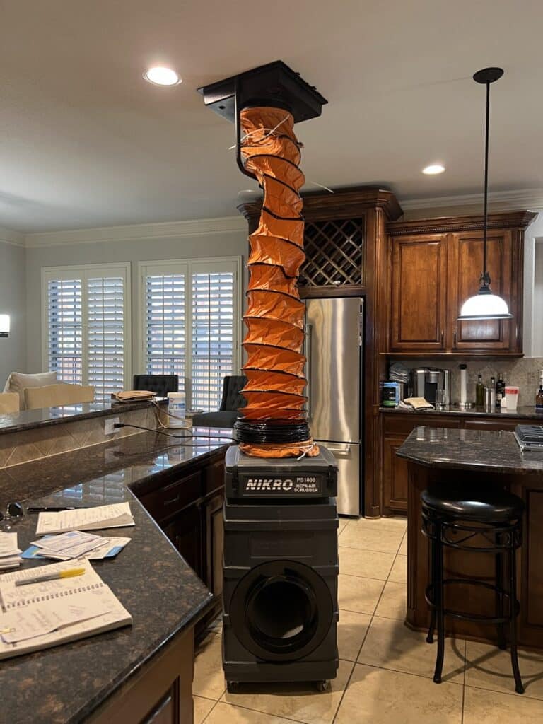 NIKRO professional duct cleaning equipment with orange hose set up in a Texas residential kitchen