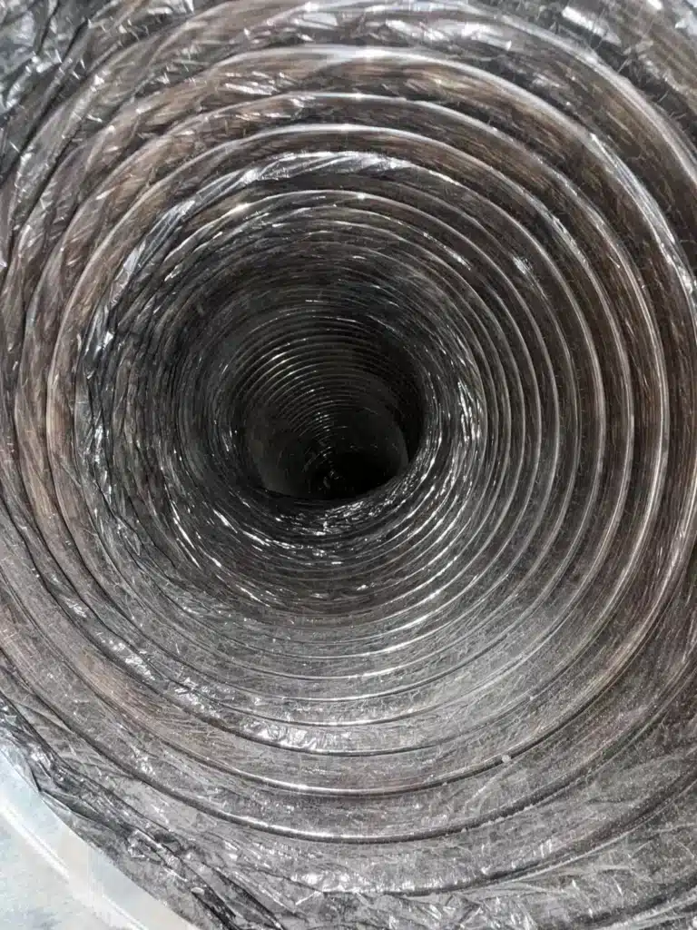 Air duct cleaning: view down a flexible duct interior with dust visible along the ribbed lining