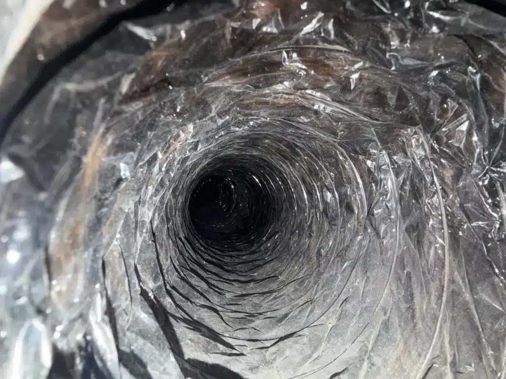 Air duct cleaning: interior of a ribbed flexible duct with dust and debris on the lining
