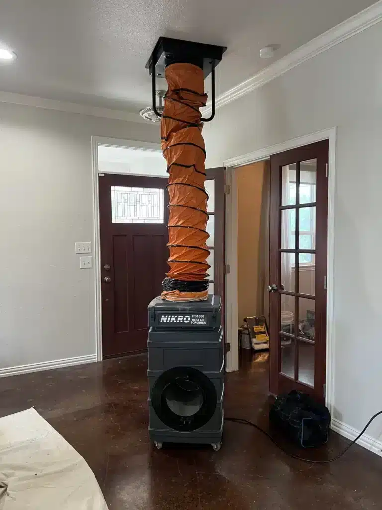 Air duct cleaning: negative air machine connected to a ceiling return with an orange collection duct