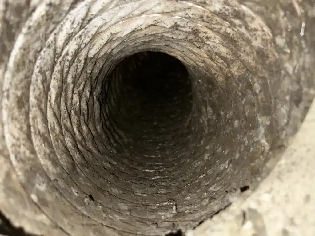 Air duct cleaning needed: interior of a duct line coated in heavy gray dust before service