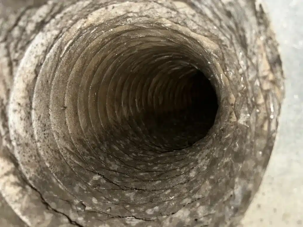 Air duct cleaning before shot: dust and debris built up along the coils of a flexible duct