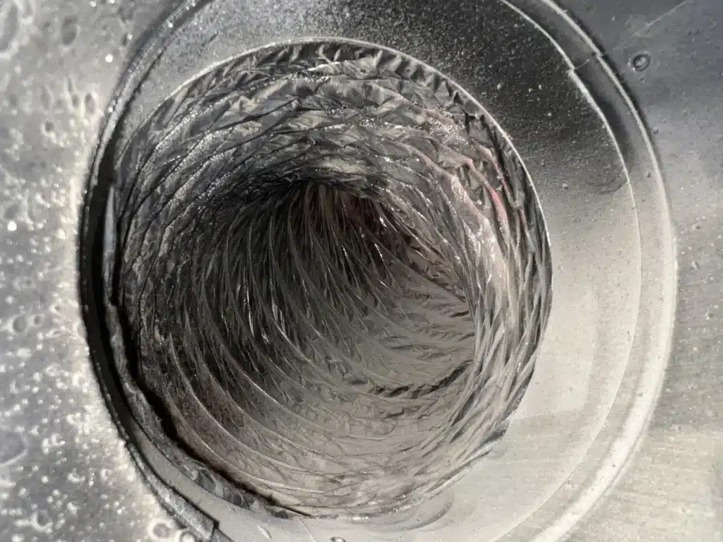 Air duct cleaning: flex duct inside a metal ceiling boot showing light residue on the liner
