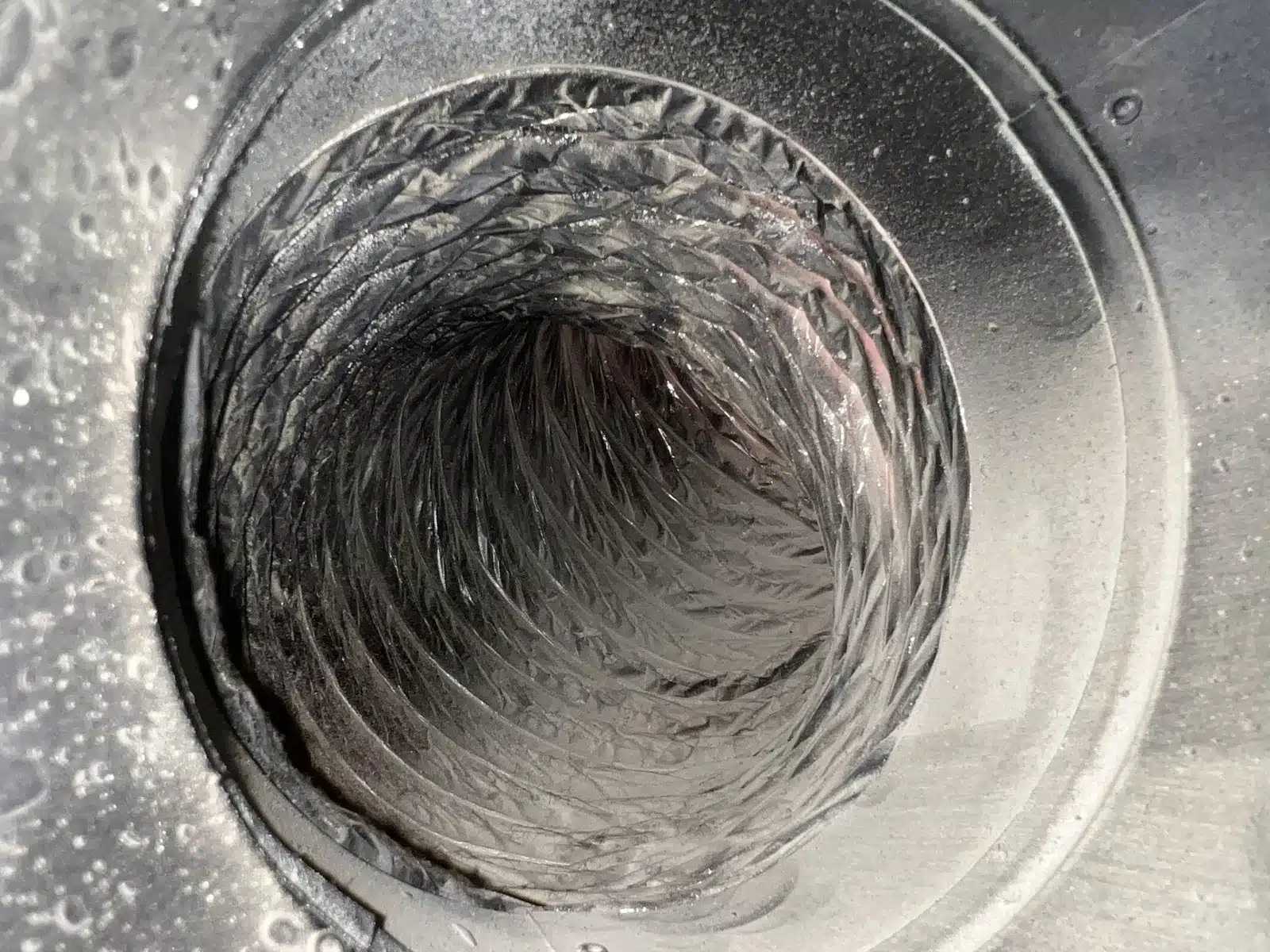 Air duct cleaning: flex duct inside a metal ceiling boot showing light residue on the liner