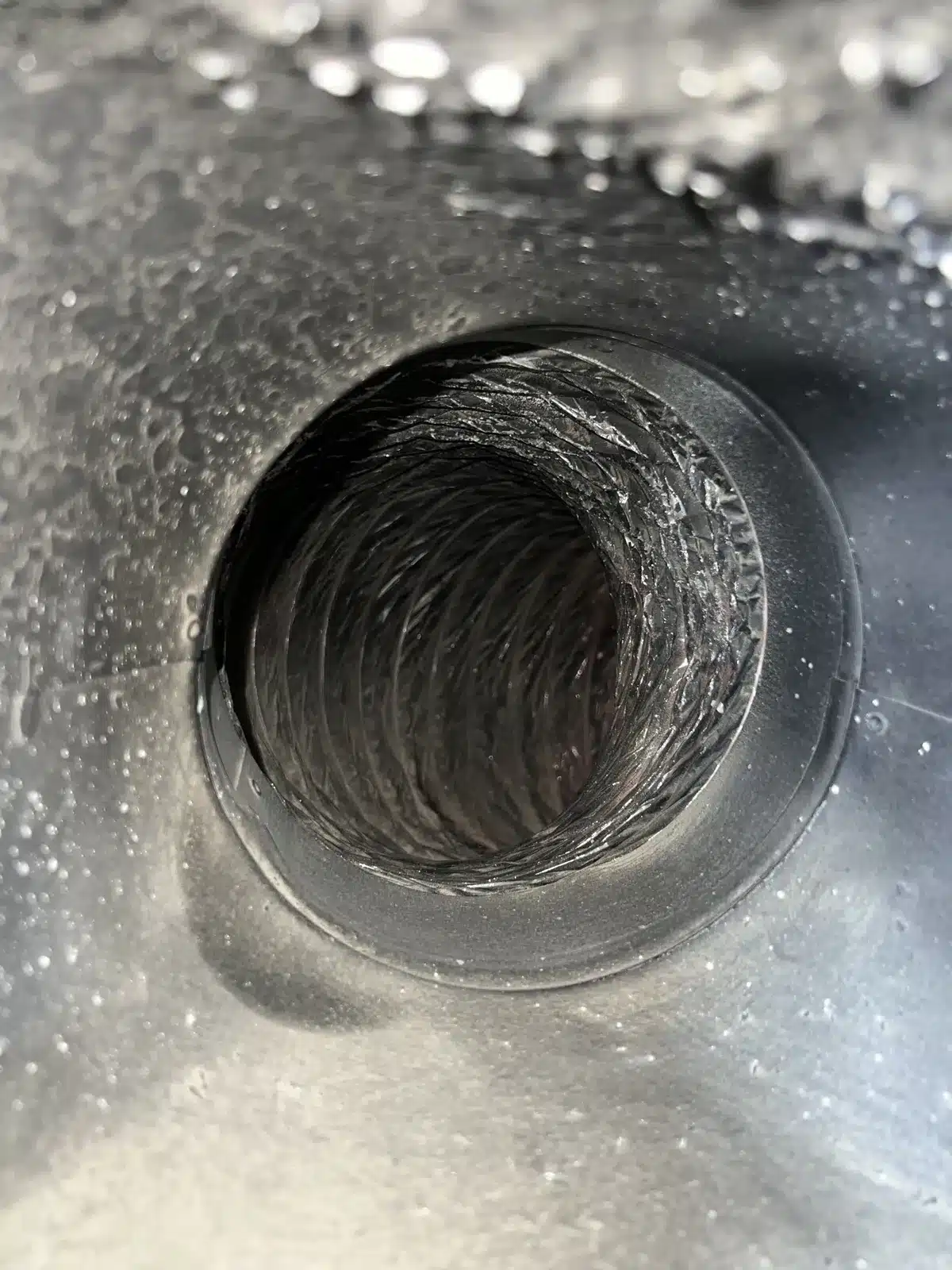 Air duct cleaning: view into a flex duct line through a round metal register boot
