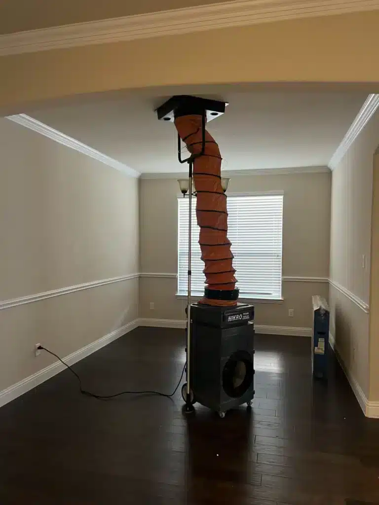 Air duct cleaning setup: sealed ceiling return vent ducted into a negative air machine in an empty room