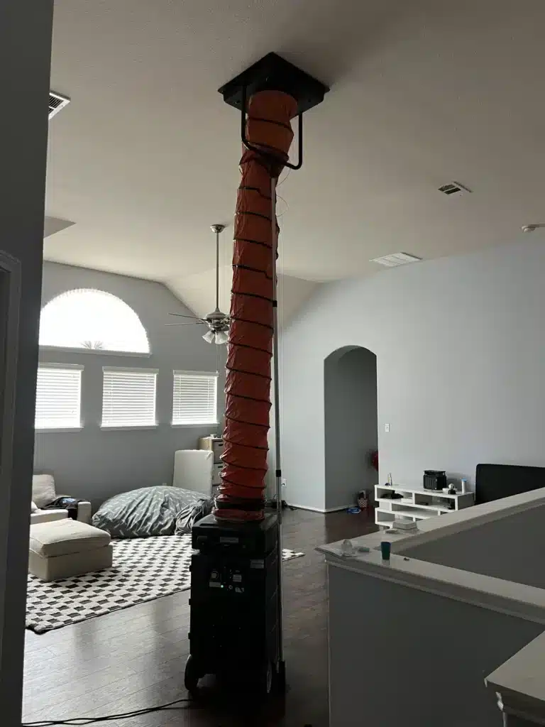 Air duct cleaning: tall orange collection duct running from a machine up to a ceiling return in a bedroom