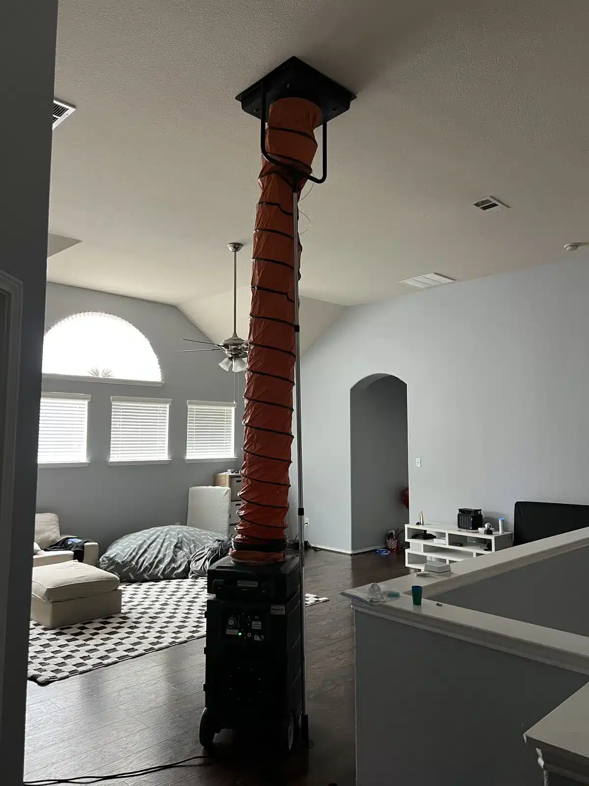 Air duct cleaning: tall orange collection duct running from a machine up to a ceiling return in a bedroom