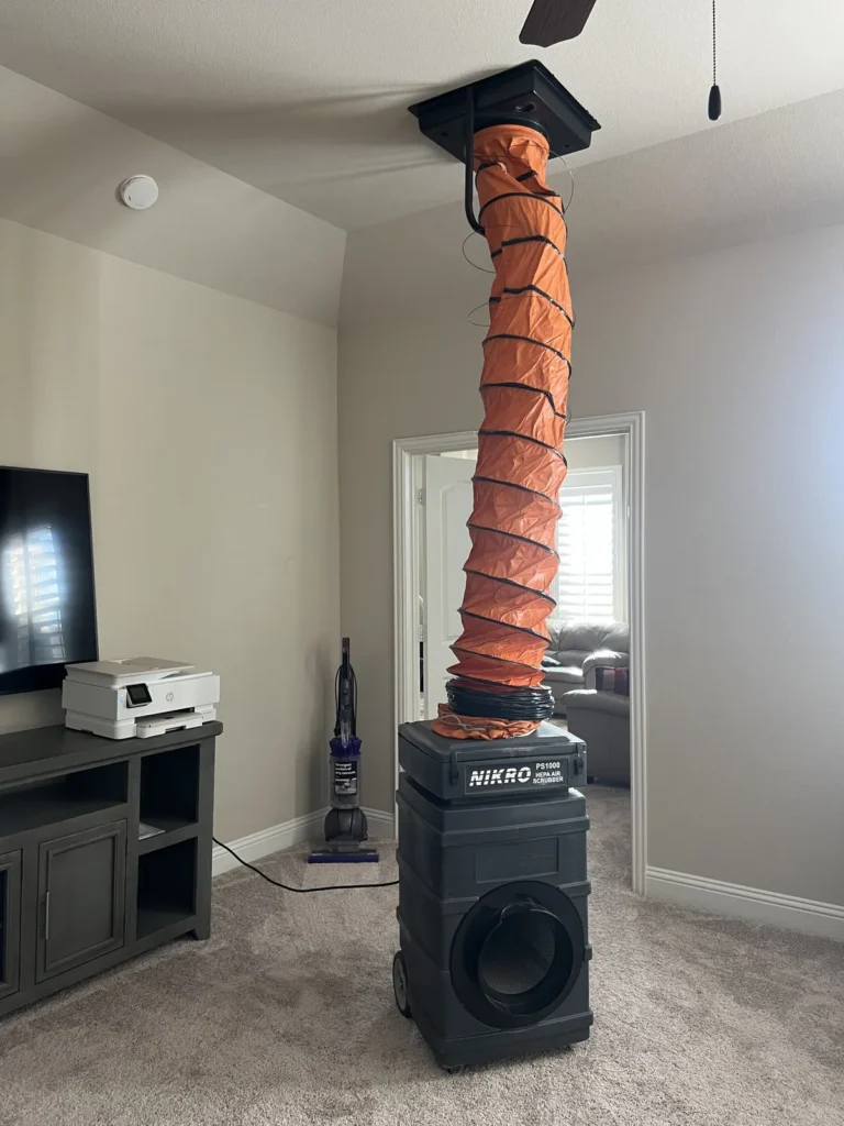 Air duct cleaning in progress: portable vacuum unit ducted to a ceiling register in a home office