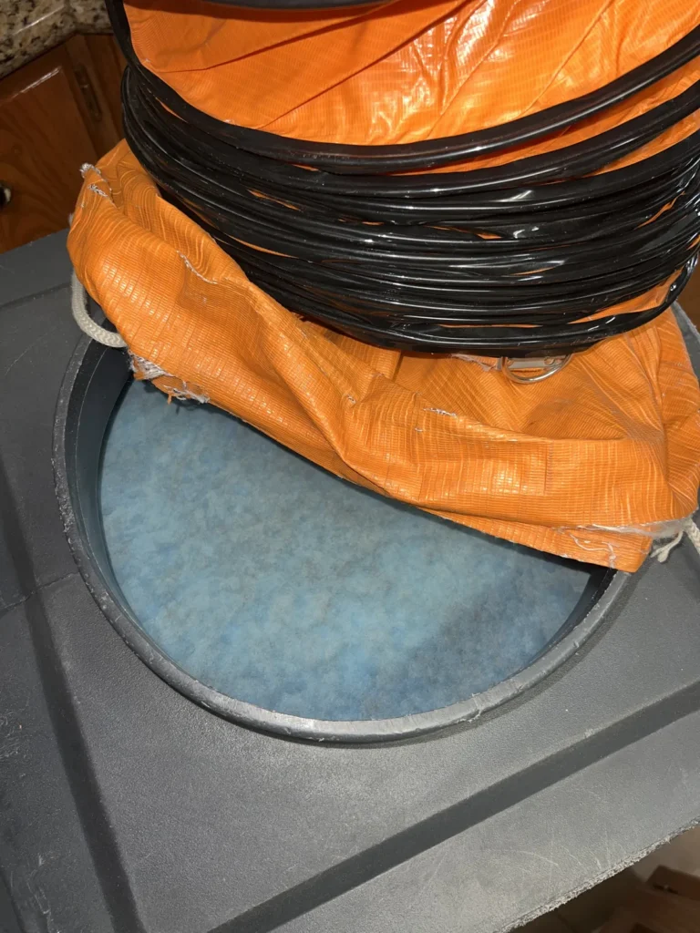 Air duct cleaning equipment close-up: orange flex duct and filter on top of a portable vacuum unit