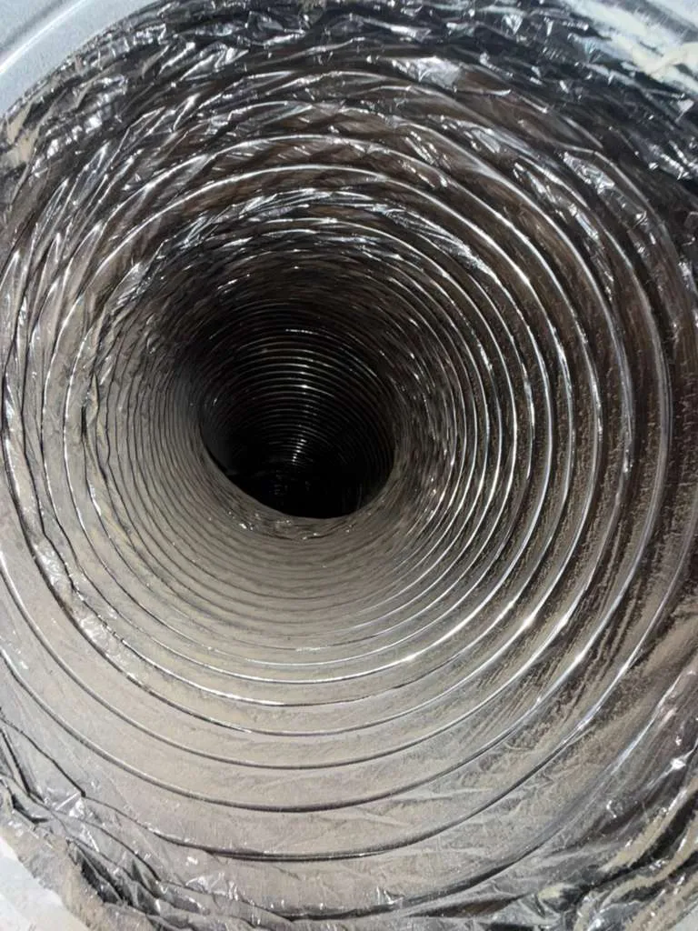Air duct cleaning: inside a foil-lined flexible duct showing the spiral coils along the run