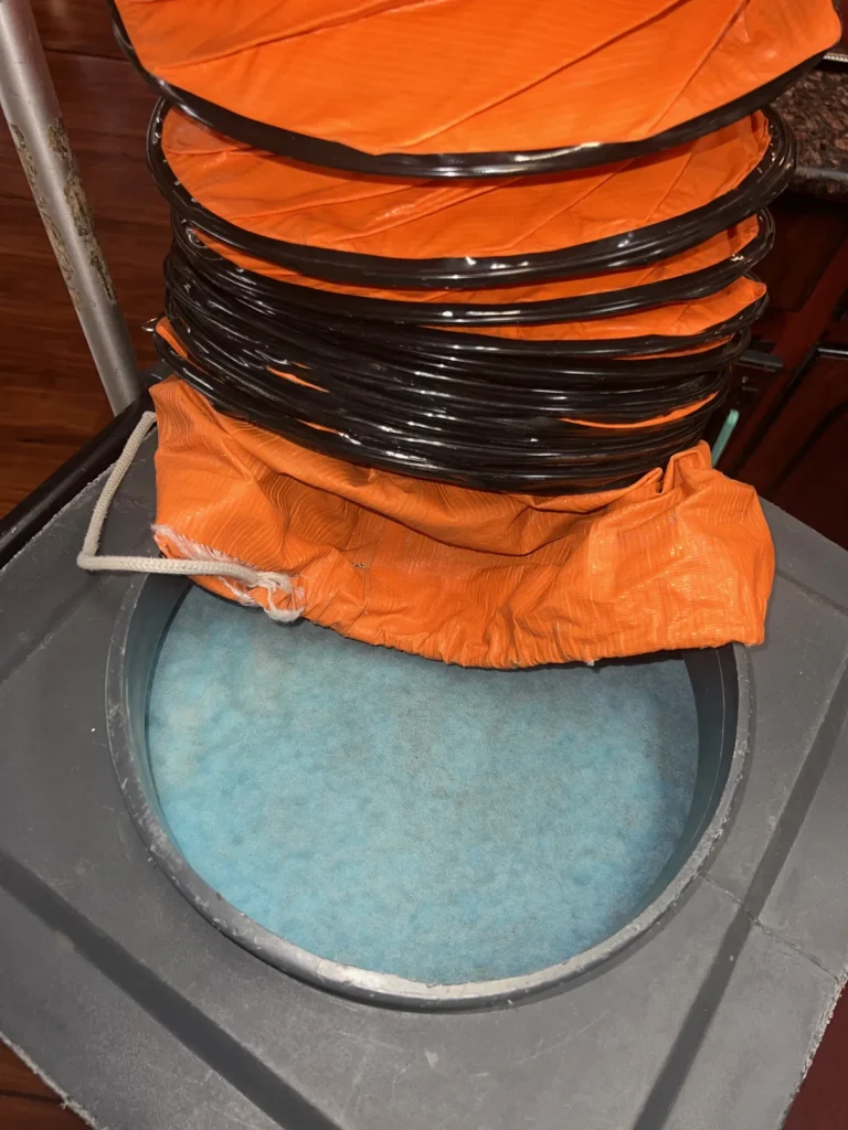 Air duct cleaning: orange collection duct attached over a housing with a blue filter inside
