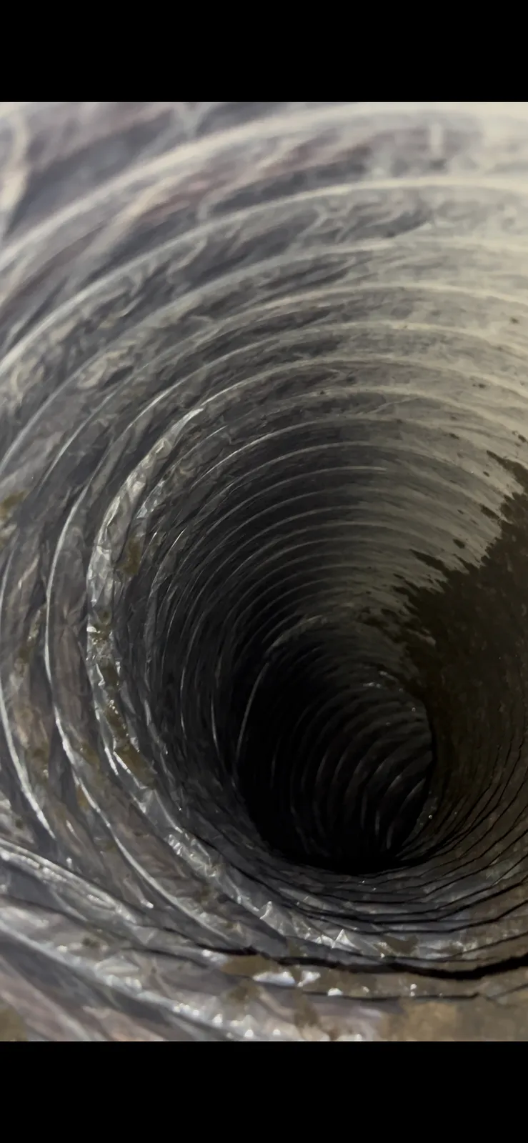 Air duct cleaning: negative air machine with orange duct sealed to the ceiling in a living room