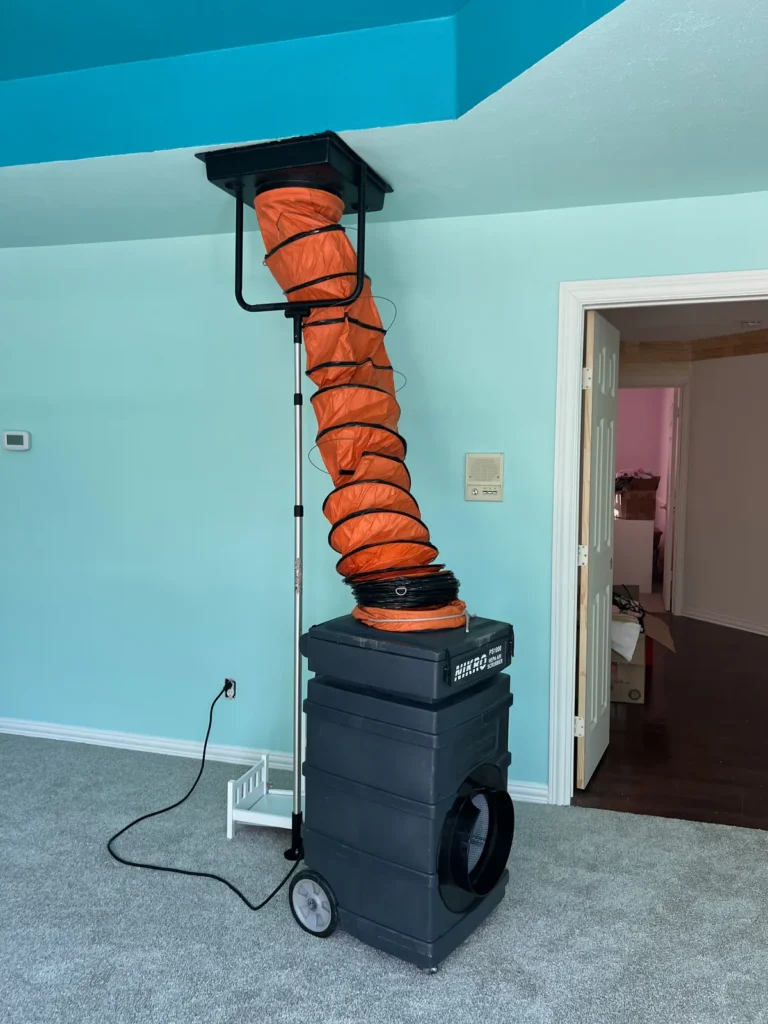 Air duct cleaning: negative air machine with orange flex hose sealed to a ceiling return in an empty room