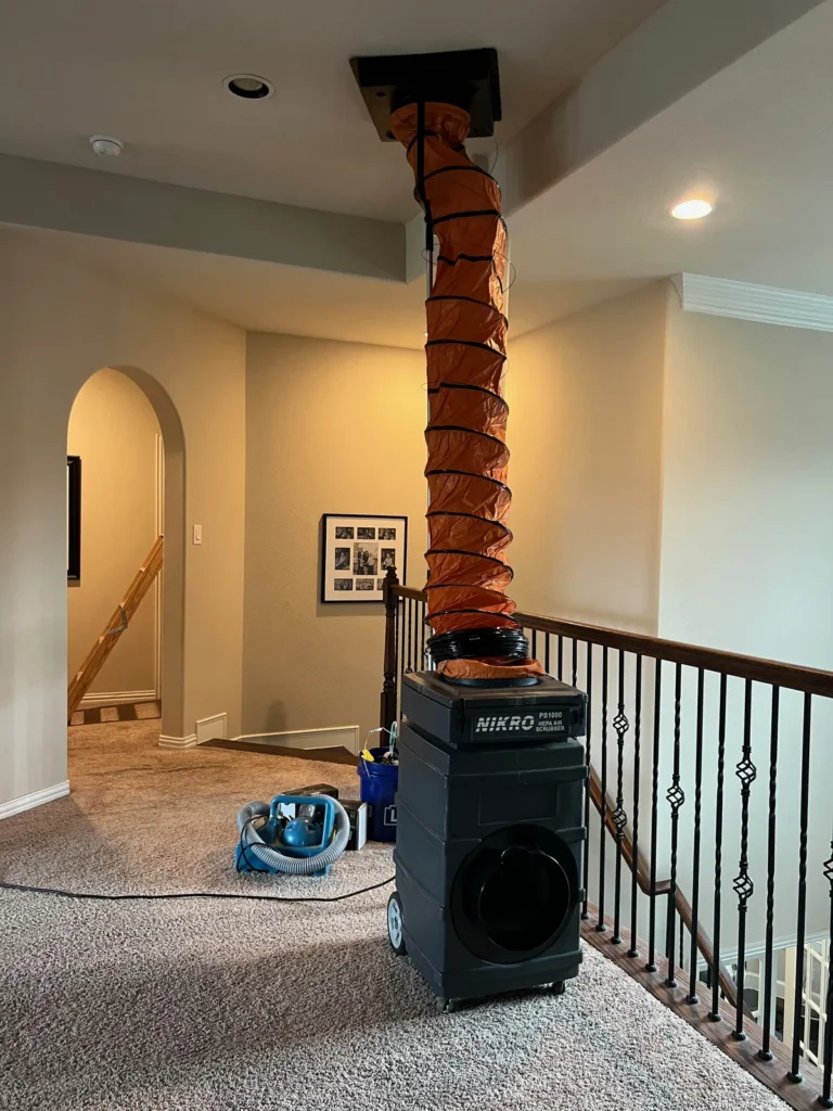 Air duct cleaning setup: negative air machine with flex hose sealed to an upstairs hallway ceiling vent