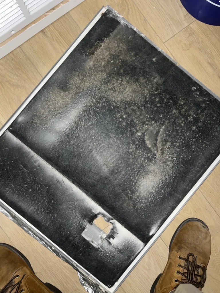 Air duct sanitizing: technician inspects a dust-caked return filter pulled from a home vent