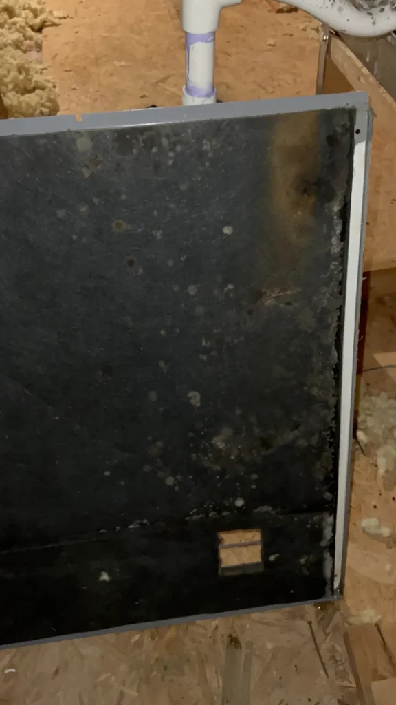 Air duct sanitizing in an attic: filter panel removed, covered in dark buildup and spotting