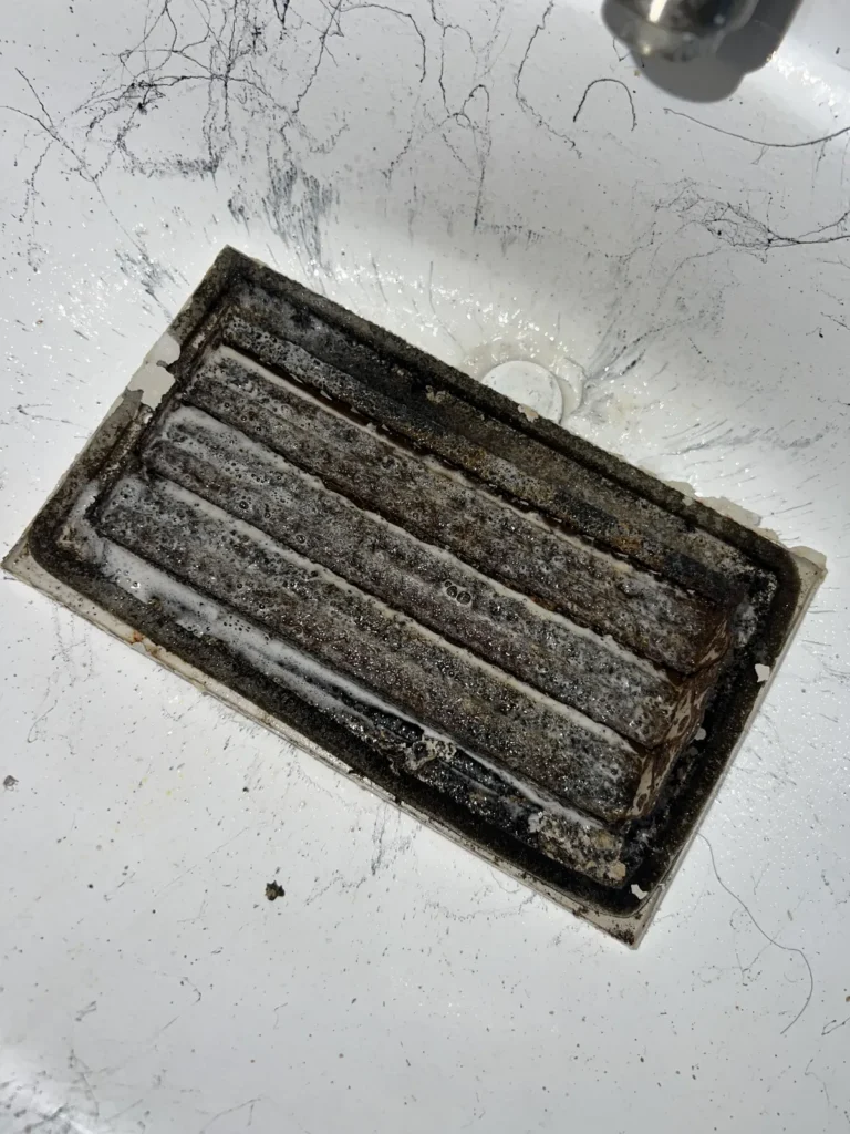 Air duct sanitizing: small vent register caked with dust and grime before cleaning