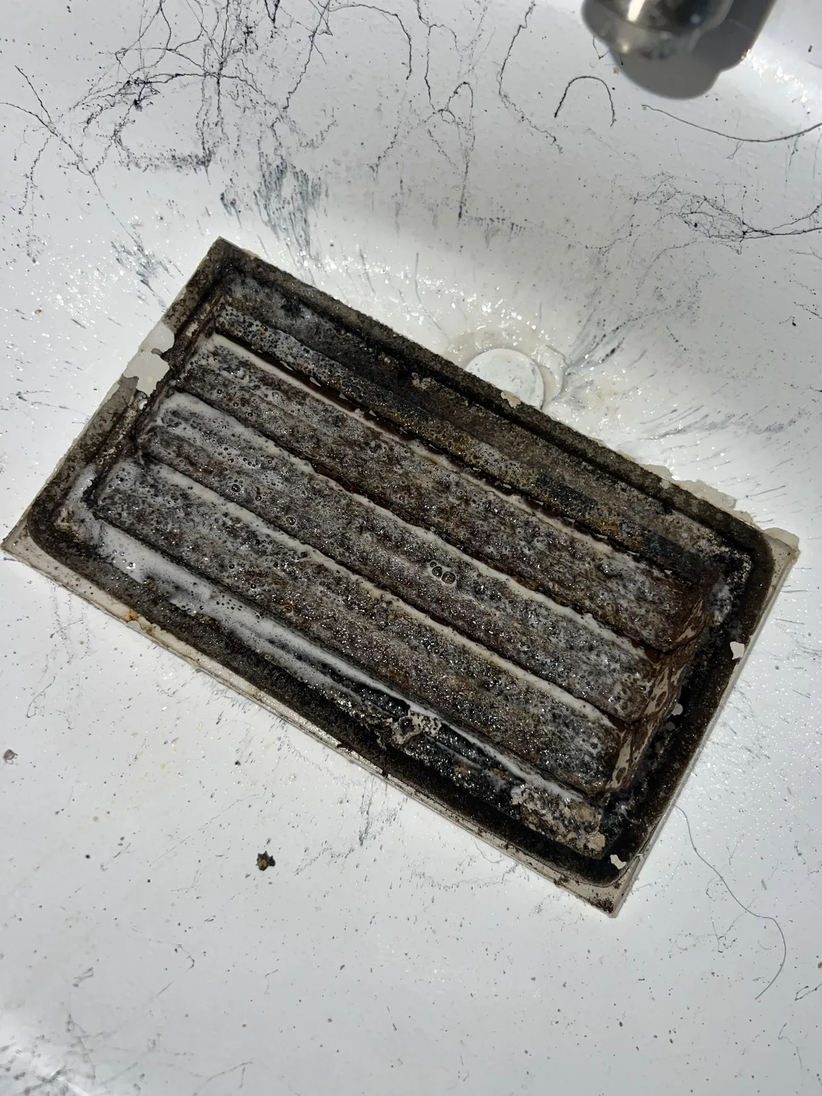 Air duct sanitizing: small vent register caked with dust and grime before cleaning