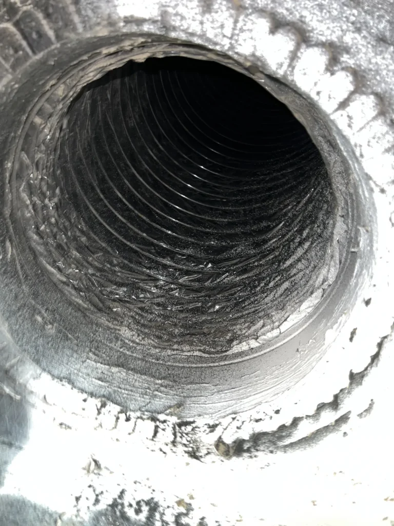 View down a round metal duct, interior coils cleared of dust after cleaning