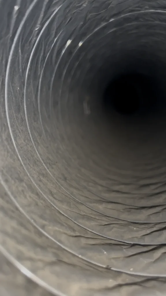 Interior of a flex duct with a light dust film on the ribbed walls