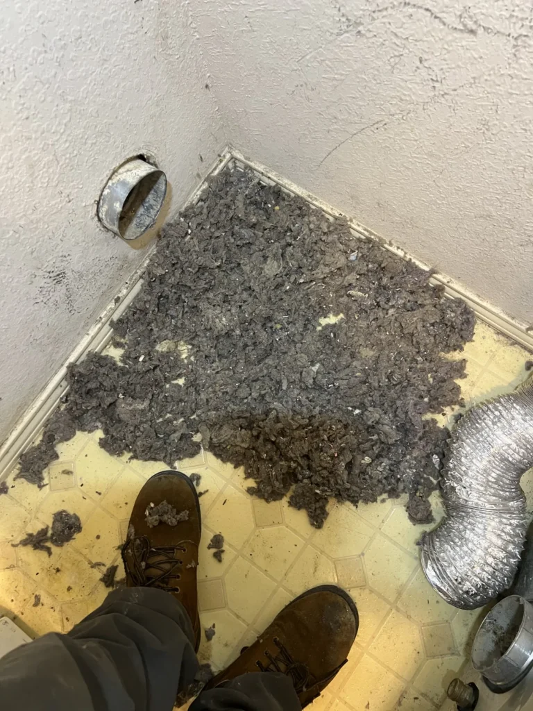 Dryer vent cleaning: large pile of lint cleared from the wall vent in a laundry corner