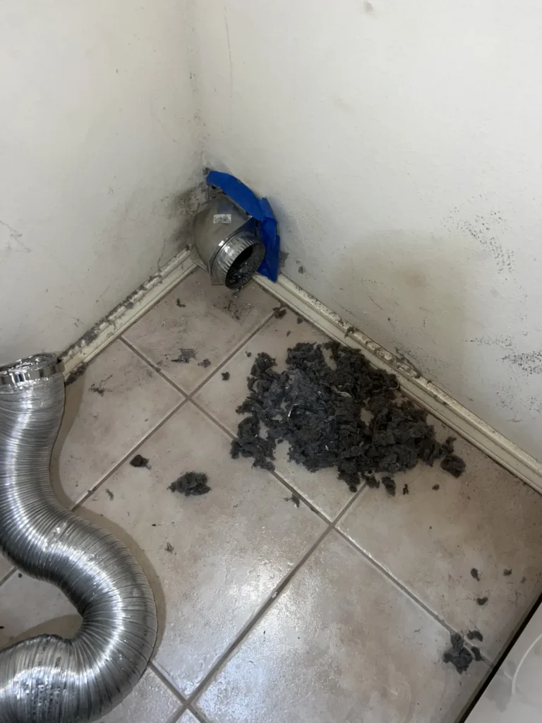 Dryer vent cleaning: lint pile pulled from the wall vent onto the laundry room tile floor