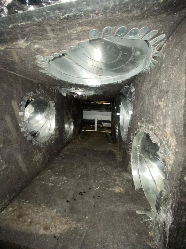 Plenum box repair: inside view of a supply plenum with metal duct collars before rebuild