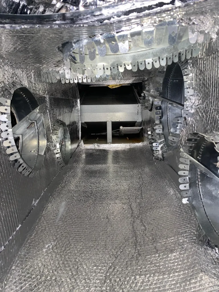 Plenum interior after cleaning and resealing, with fresh foil lining and sealed duct collar tabs