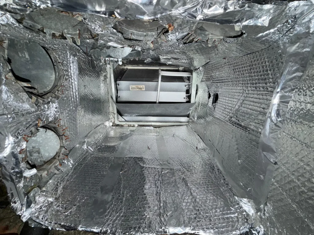 Clean foil-lined plenum interior after service, the chamber that sits directly on the furnace or air handler
