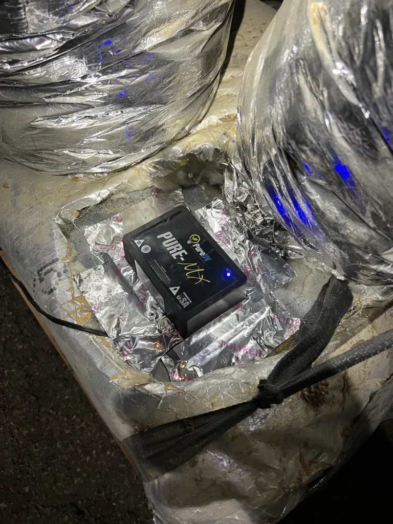 UV light installation: Pure-MX unit sealed to insulated ductwork with a blue glow visible inside the ducts