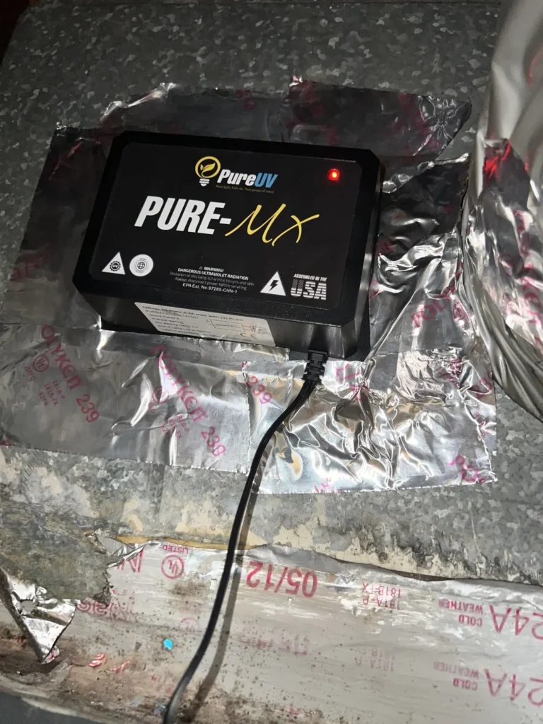 UV light installation: close-up of a Pure-MX purifier taped to a duct with its indicator light on