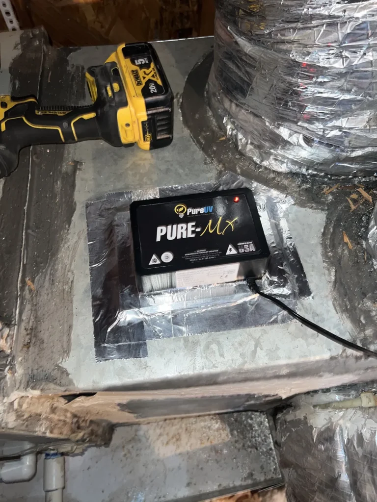 UV light installation: Pure-MX purifier mounted on a sealed duct board with a cordless drill nearby