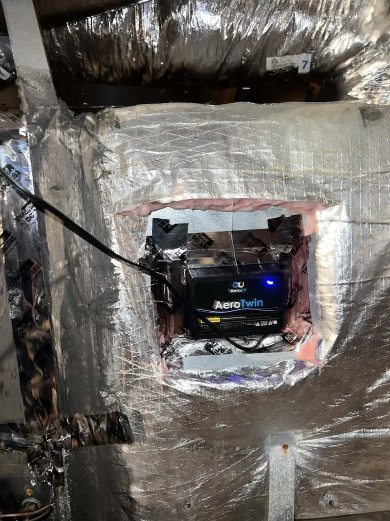 UV light installation: AeroTwin purifier unit mounted inside a foil-wrapped plenum opening