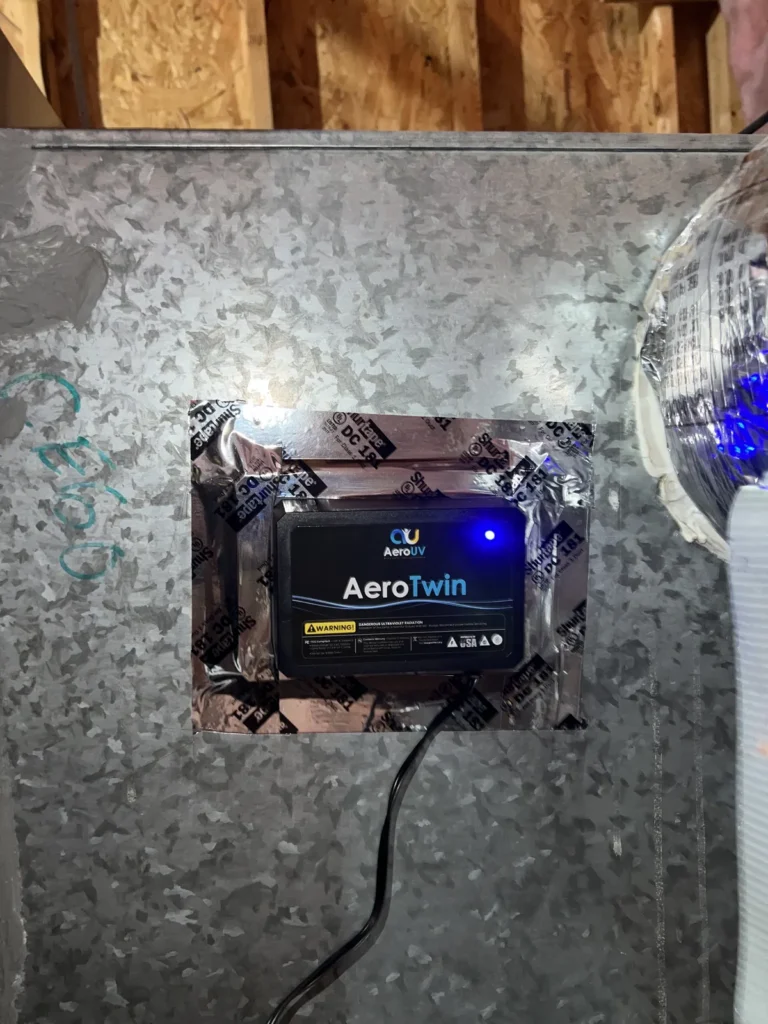 UV light installation: AeroTwin unit with indicator light mounted on a galvanized air handler panel