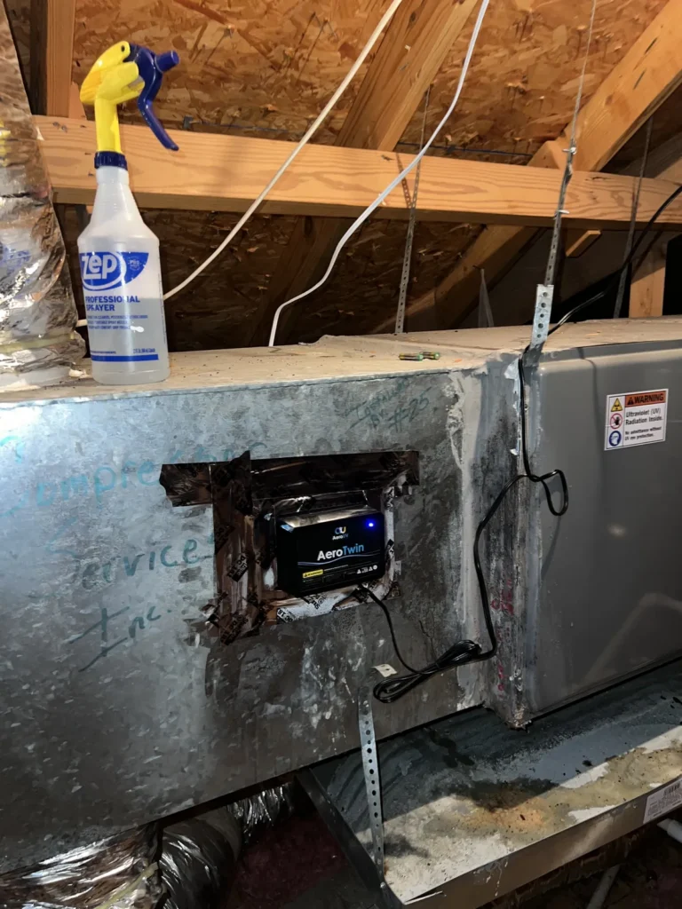 UV light installation: AeroTwin purifier sealed into a metal plenum in an attic with roof framing above