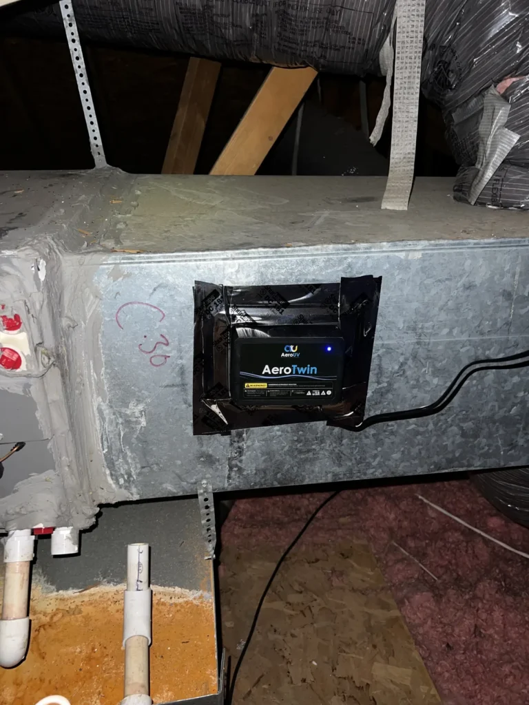 UV light installation: AeroTwin unit taped and sealed onto a metal supply plenum in an attic