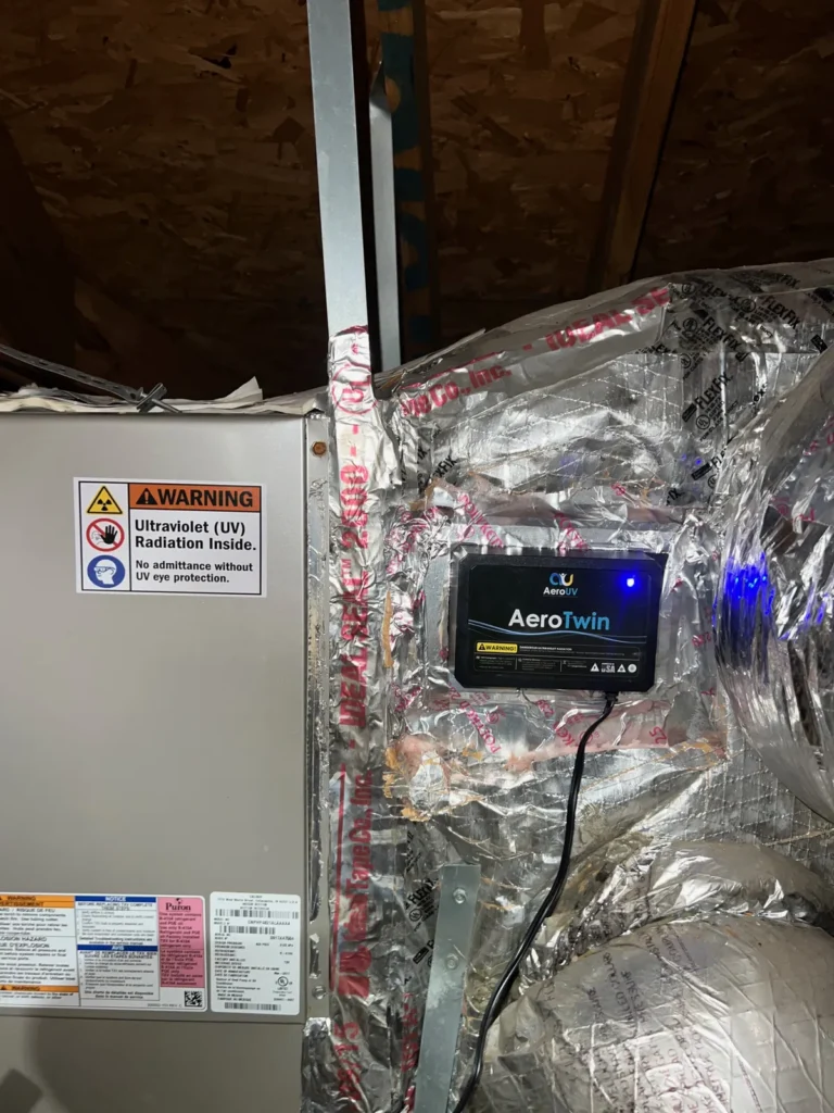 UV light installation: AeroTwin unit on foil-wrapped ductwork next to an air handler with UV warning label